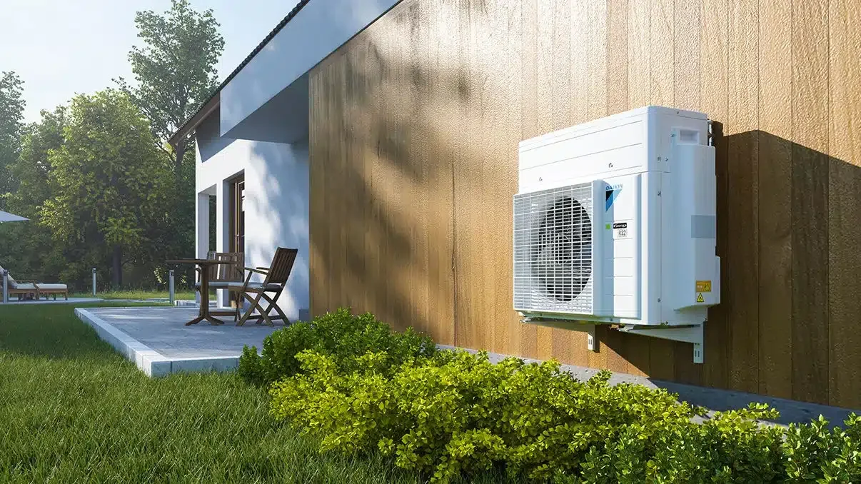 Warmtepomp naast een woning met houten gevel