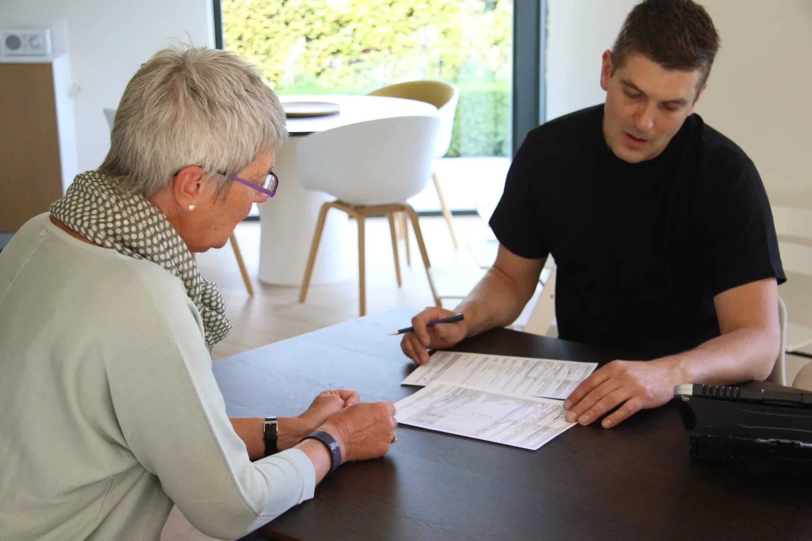 Pattyn-medewerker bespreekt documenten met een klant aan tafel