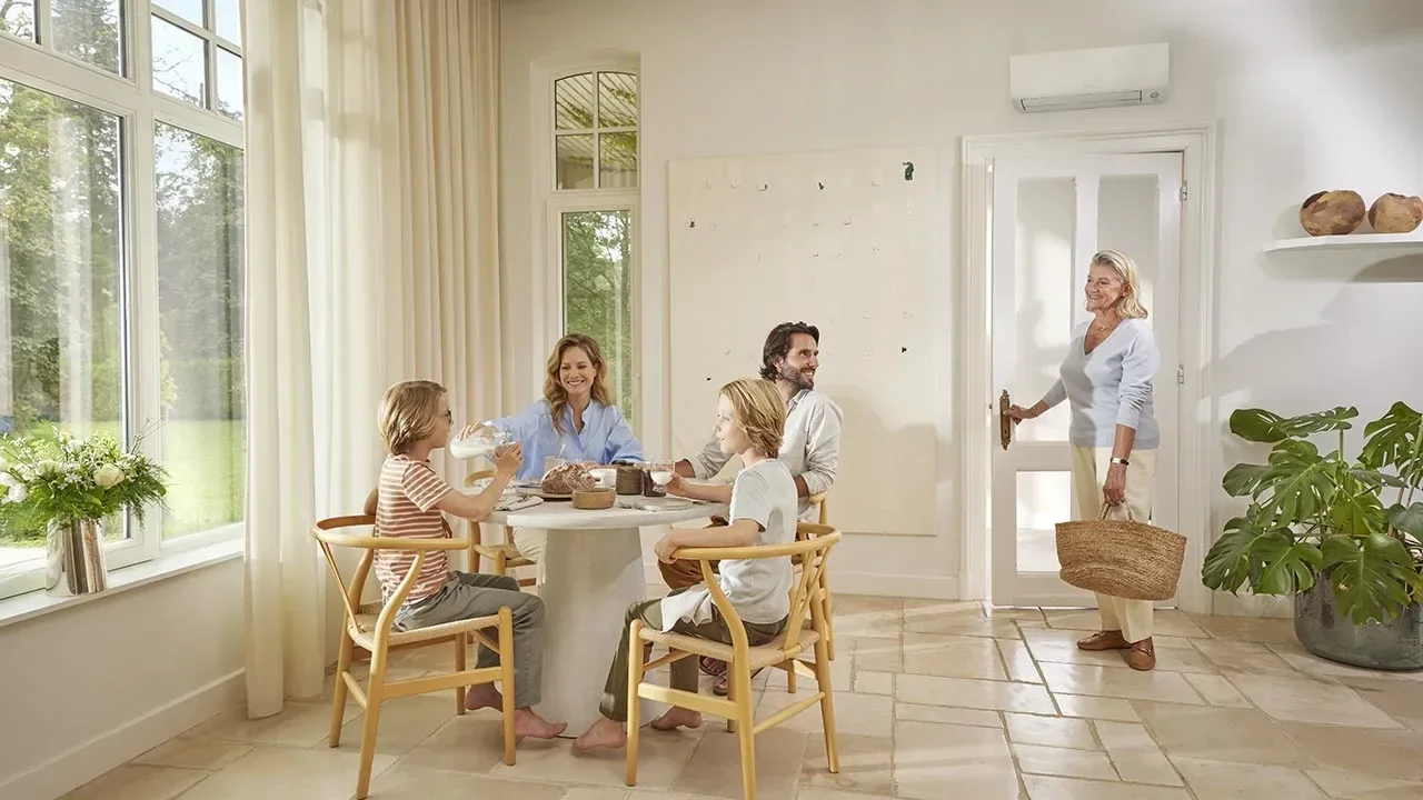 Een lichte woonruimte met een gezin aan tafel en een wandairco