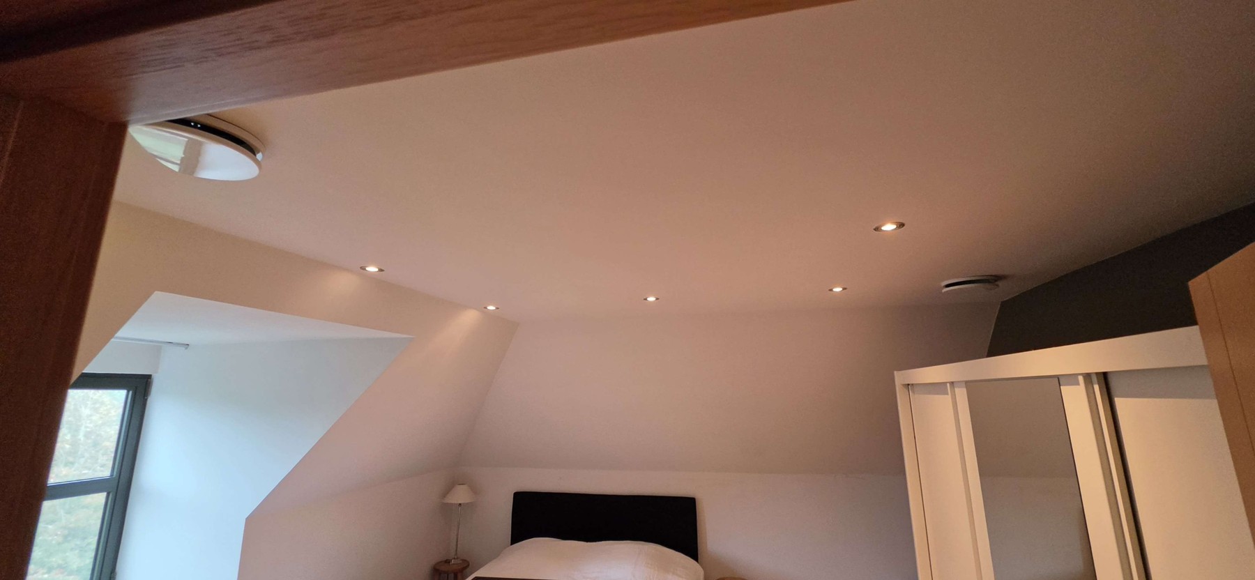 Ronde plafondroosters in een slaapkamer met schuin dak in Damme
